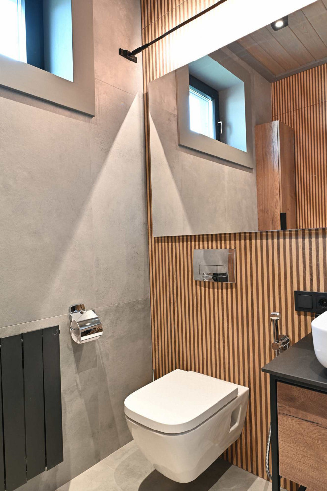 Idéer för mellanstora funkis svart toaletter, med skåp i mellenmörkt trä, en vägghängd toalettstol, beige kakel, porslinskakel, grå väggar, klinkergolv i porslin, ett fristående handfat, kaklad bänkskiva och grått golv