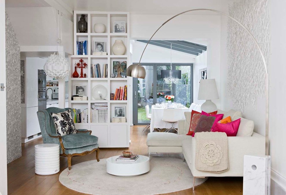 Transitional enclosed living room in London with a library, white walls and medium hardwood floors.