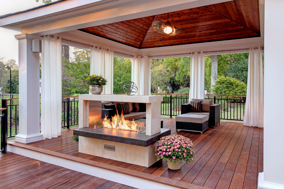 Photo of a large contemporary backyard deck in Other with a fire feature and a pergola.