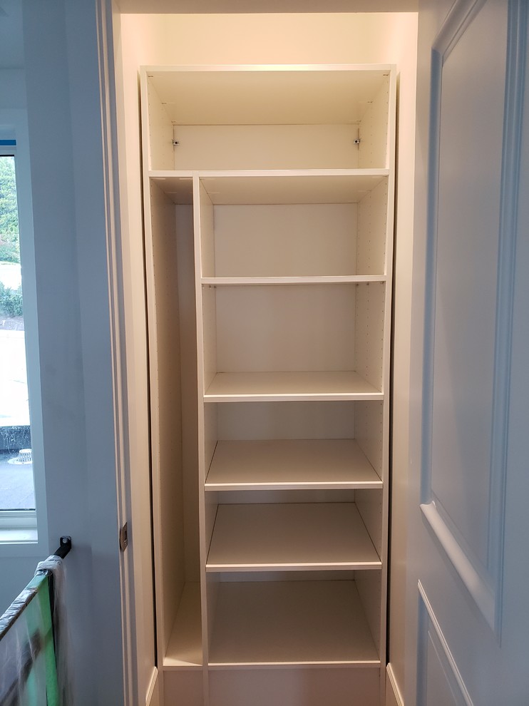 This is an example of a mid-sized modern gender-neutral built-in wardrobe in Vancouver with raised-panel cabinets and white cabinets.