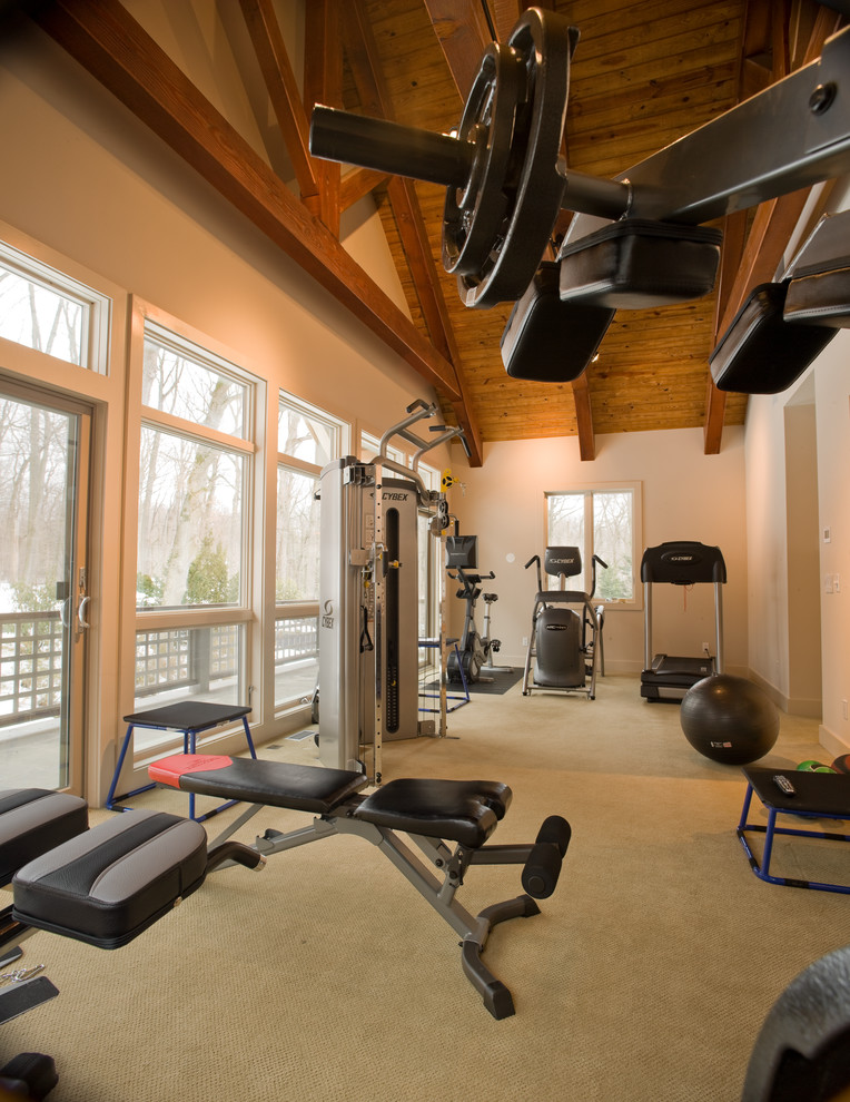 This is an example of a mid-sized contemporary home weight room in Other with exposed beam, grey walls, carpet and brown floor.