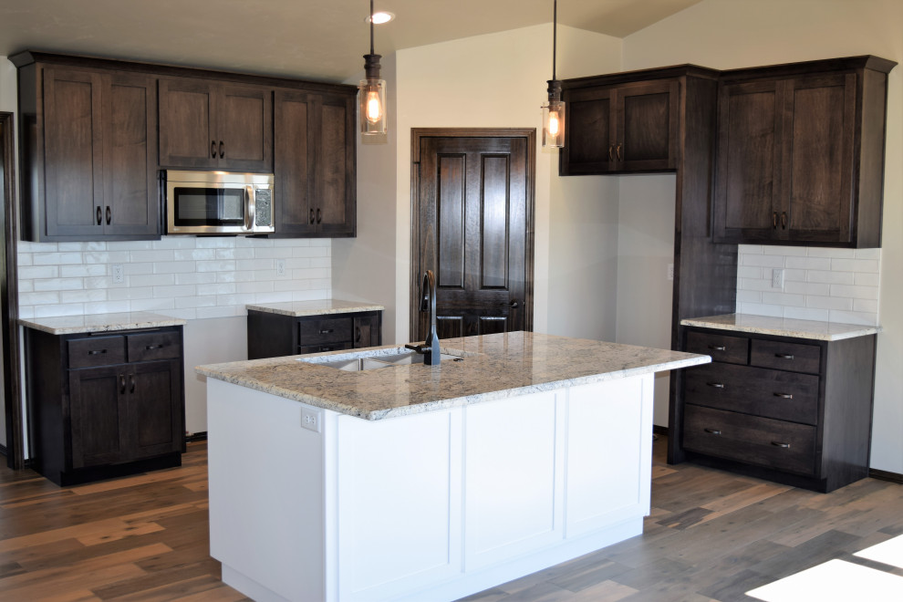 Inspiration for a large l-shaped medium tone wood floor, brown floor and vaulted ceiling open concept kitchen remodel with an undermount sink, recessed-panel cabinets, granite countertops, white backsplash, ceramic backsplash and an island