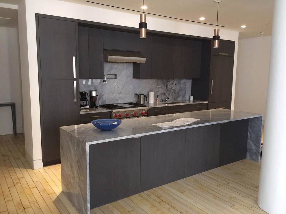 This is an example of a mid-sized contemporary single-wall eat-in kitchen in New York with a drop-in sink, flat-panel cabinets, black cabinets, grey splashback, stainless steel appliances and with island.