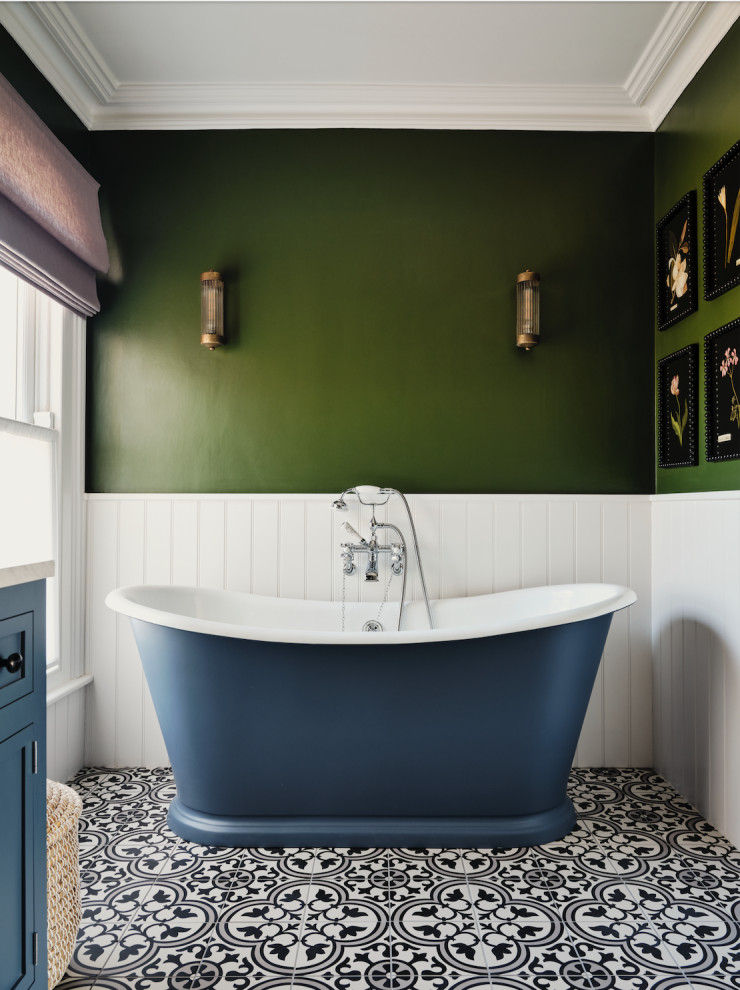 Large transitional master bathroom in London with shaker cabinets, blue cabinets, a freestanding tub, green walls, porcelain floors, marble benchtops, multi-coloured floor, a single vanity, a freestanding vanity and panelled walls.