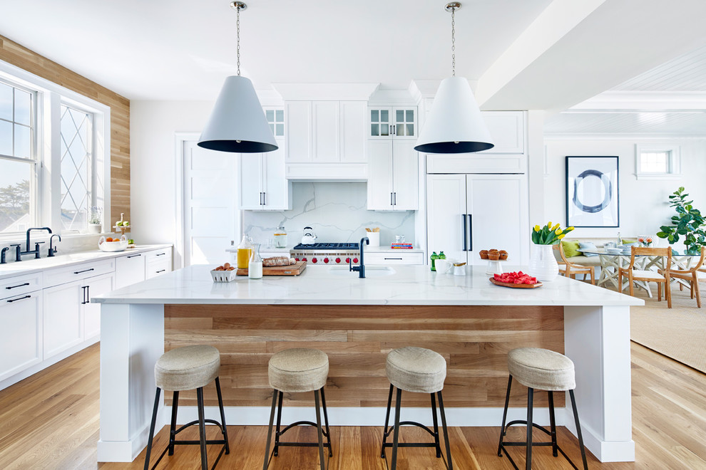 Beach style l-shaped medium tone wood floor and brown floor kitchen photo in New York with an integrated sink, shaker cabinets, white cabinets, brown backsplash, wood backsplash, stainless steel appliances, an island and white countertops
