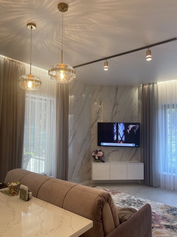 Пример оригинального дизайна: гостиная комната в современном стиле с белыми стенами, полом из керамогранита, телевизором на стене, зоной отдыха и белым полом