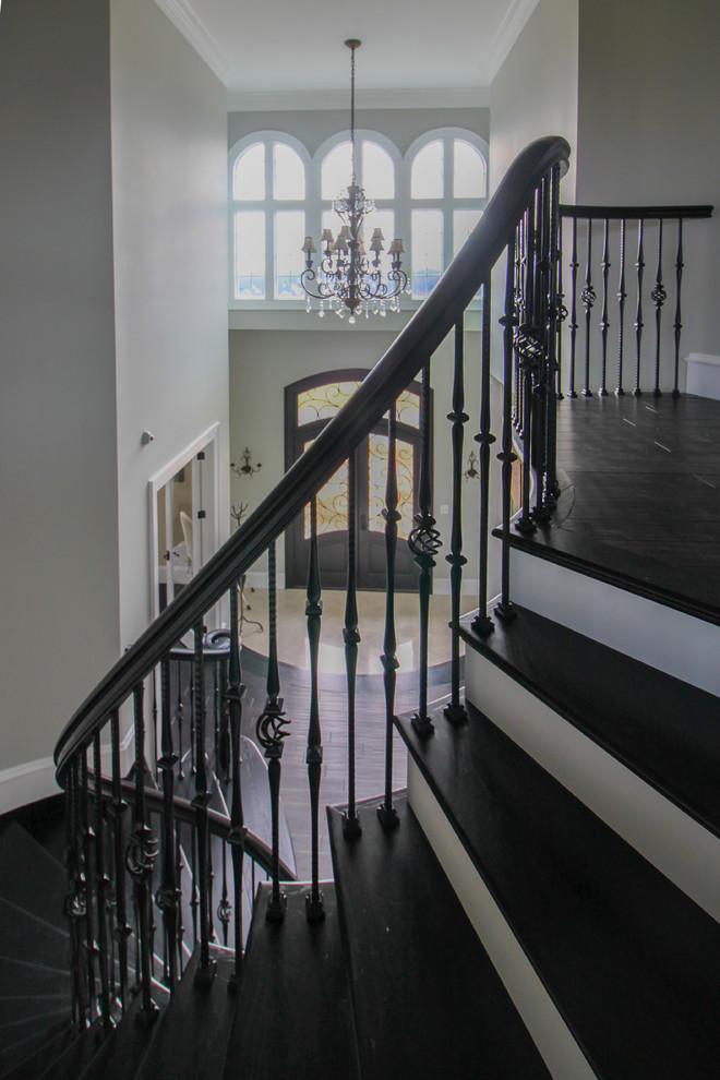 Photo of an expansive transitional wood curved staircase in DC Metro with wood risers and mixed railing.