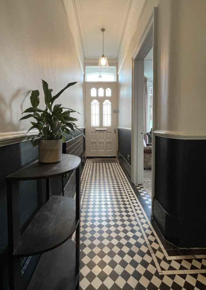 This is an example of a mid-sized arts and crafts entry hall in London with black walls, ceramic floors, a single front door, a white front door, black floor, wallpaper and wallpaper.