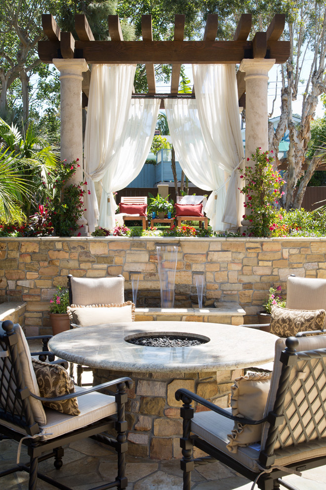 Inspiration for a mediterranean backyard patio in San Diego with natural stone pavers, a water feature and a pergola.