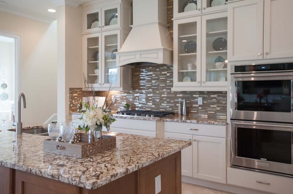Inspiration for a large transitional galley ceramic tile open concept kitchen remodel in Jacksonville with a drop-in sink, glass-front cabinets, white cabinets, quartz countertops, brown backsplash, ceramic backsplash, stainless steel appliances and two islands