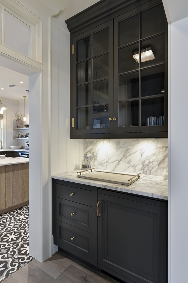 Photo of a mid-sized country single-wall wet bar in Charleston with no sink, recessed-panel cabinets, black cabinets, marble benchtops, multi-coloured splashback, stone slab splashback, medium hardwood floors, brown floor and white benchtop.