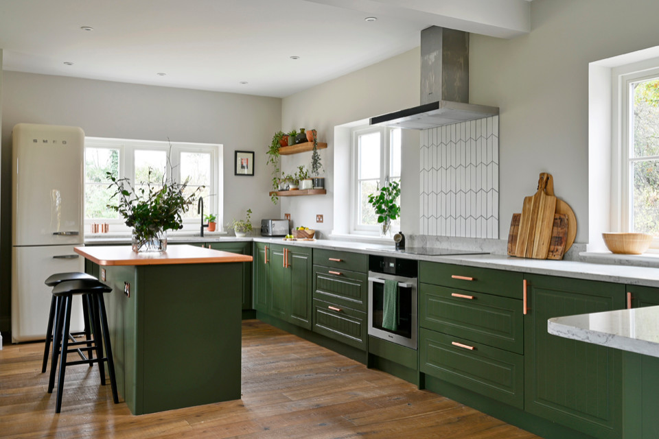 Photo of a mid-sized scandinavian u-shaped open plan kitchen in Other with an integrated sink, green cabinets, white splashback, ceramic splashback, stainless steel appliances, medium hardwood floors, with island, brown floor, white benchtop and quartzite benchtops.