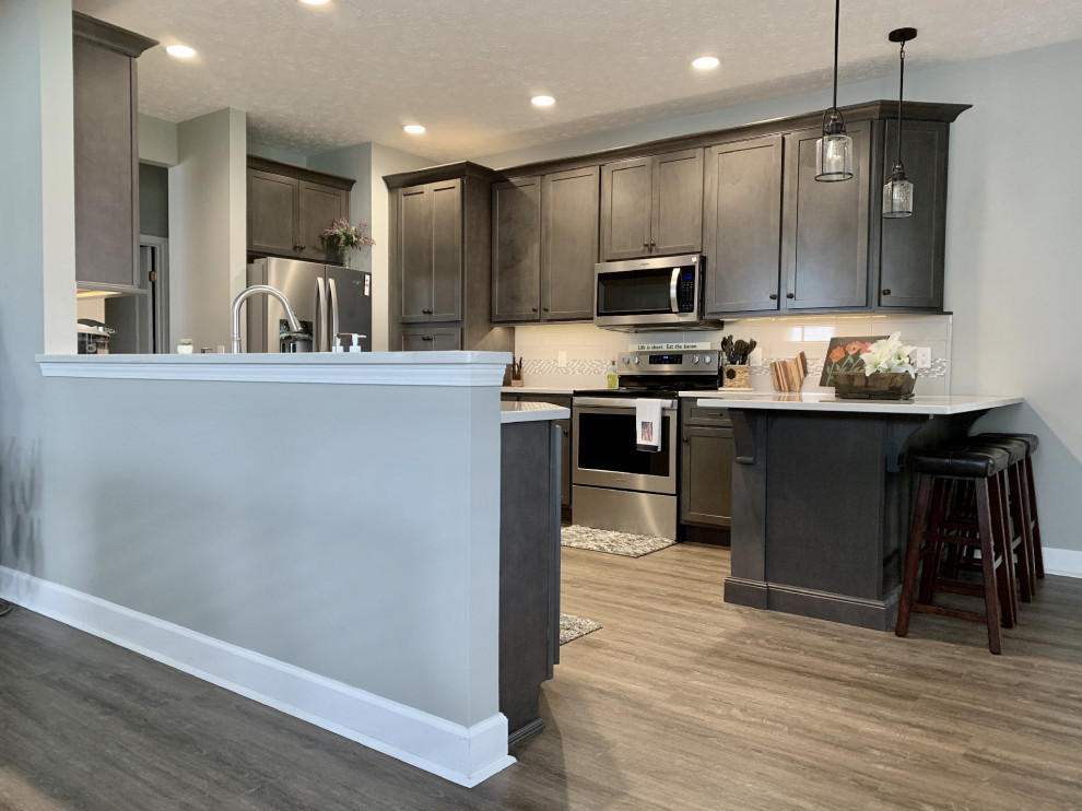 Example of a large transitional u-shaped vinyl floor and gray floor open concept kitchen design with an undermount sink, shaker cabinets, gray cabinets, quartz countertops, gray backsplash, ceramic backsplash, stainless steel appliances, a peninsula and white countertops