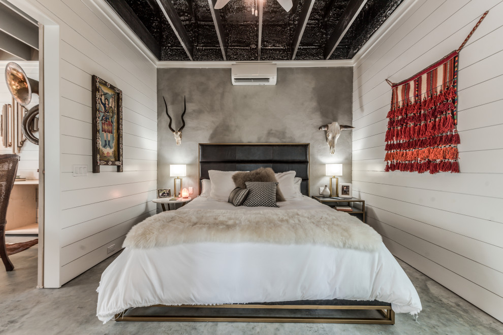 Ejemplo de dormitorio principal bohemio de tamaño medio con paredes blancas, suelo de cemento, suelo gris y machihembrado