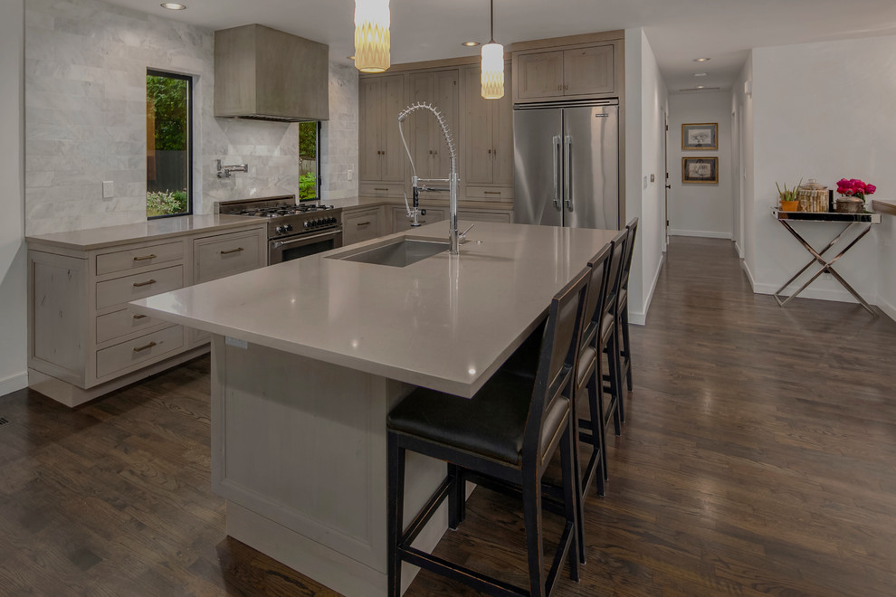 This is an example of a mid-sized l-shaped open plan kitchen in Seattle with a single-bowl sink, beaded inset cabinets, grey cabinets, quartz benchtops, white splashback, stone tile splashback, stainless steel appliances, dark hardwood floors and with island.