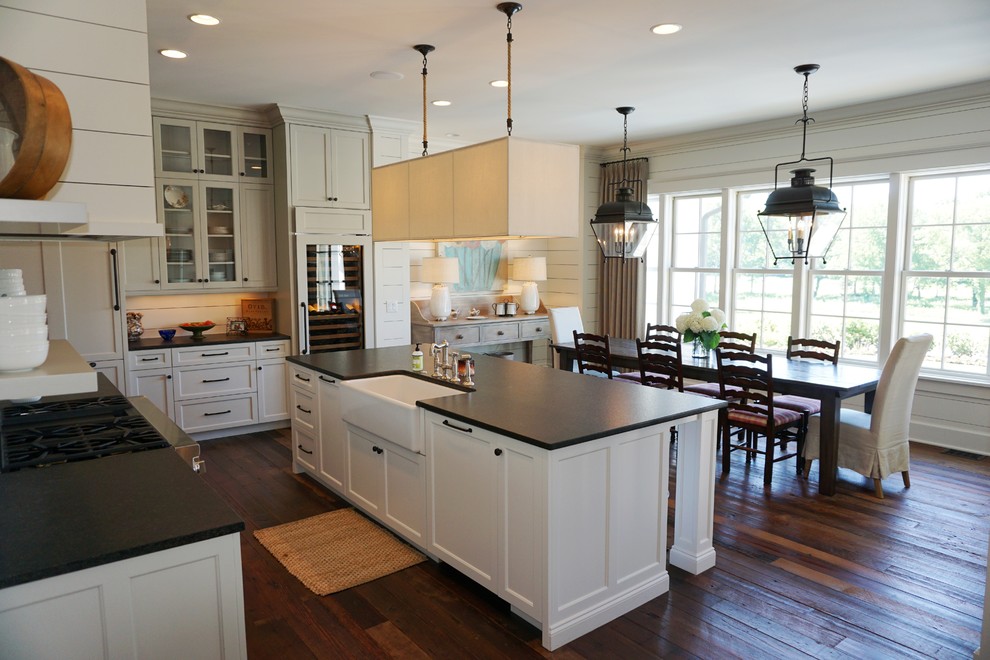 Inspiration for a large traditional l-shaped eat-in kitchen in Nashville with a farmhouse sink, recessed-panel cabinets, white cabinets, granite benchtops, white splashback, stainless steel appliances, medium hardwood floors and with island.