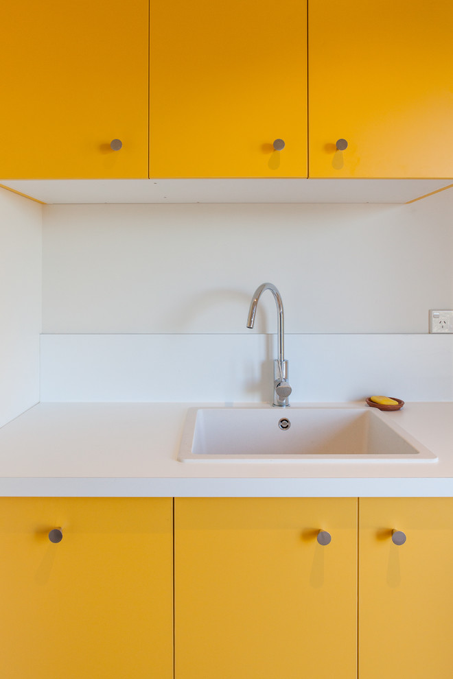 Photo of a mid-sized contemporary galley dedicated laundry room in Hamilton with yellow cabinets.