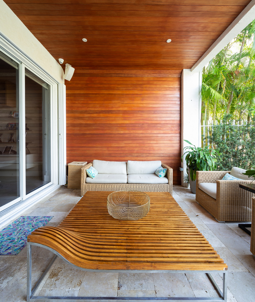 Tropical patio in Miami with natural stone pavers and a roof extension.