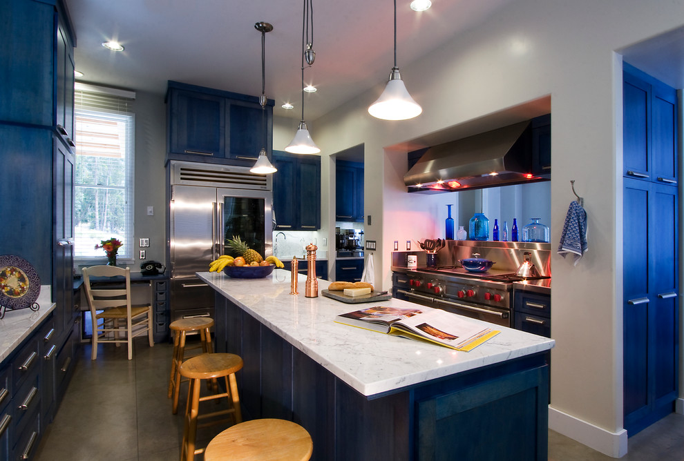 Photo of a mid-sized contemporary l-shaped separate kitchen in San Luis Obispo with stainless steel appliances, shaker cabinets, blue cabinets, marble benchtops, white splashback, stone slab splashback, concrete floors, with island and grey floor.