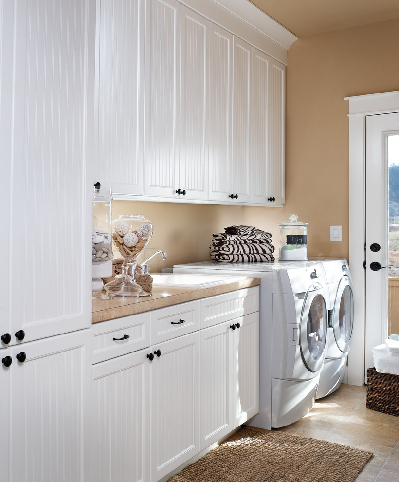 Design ideas for a traditional laundry room in Portland with white cabinets.