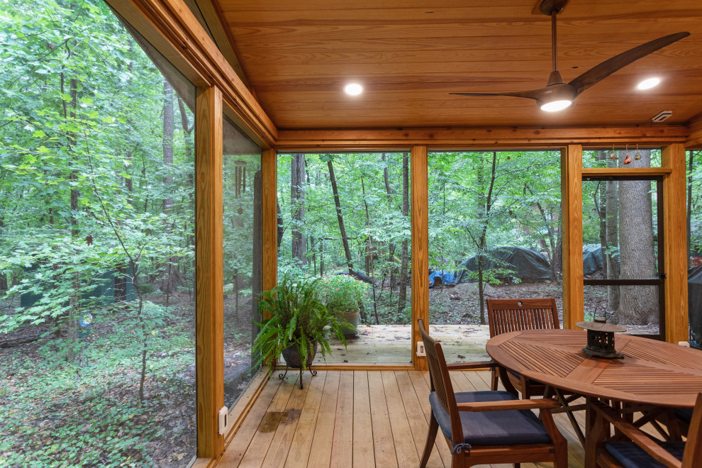 Exemple d'un grand porche d'entrée de maison arrière montagne avec une moustiquaire, une terrasse en bois et une extension de toiture.