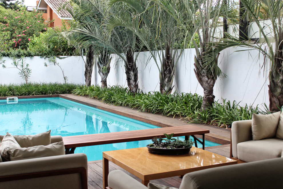 Foto de piscina alargada moderna grande rectangular en patio trasero con entablado