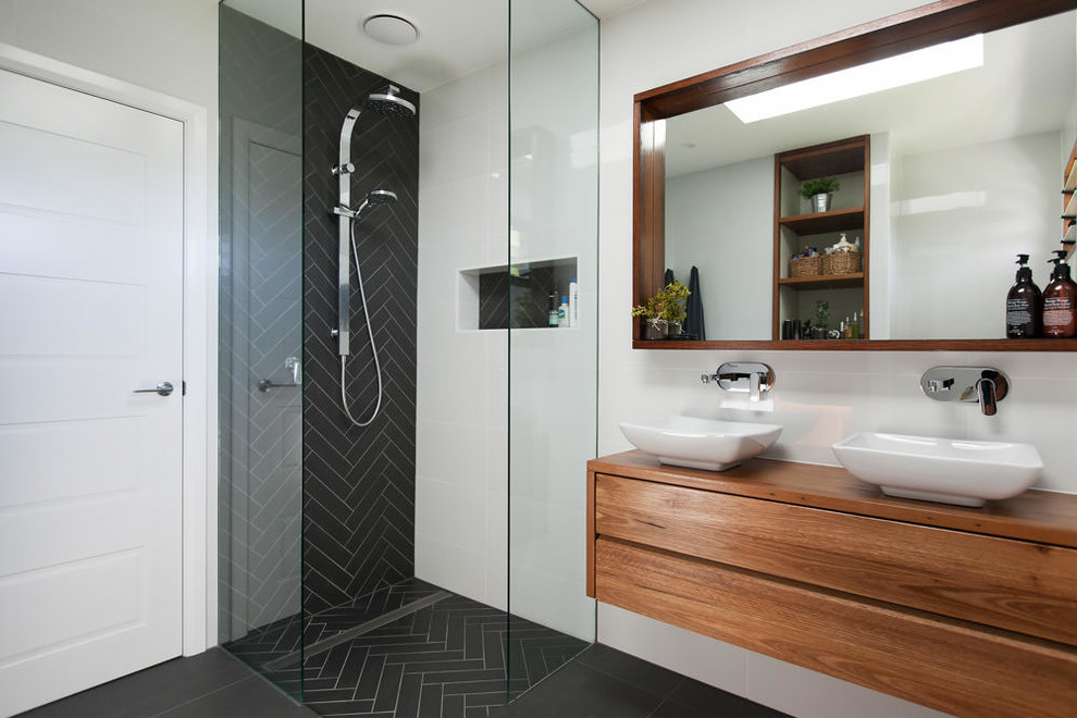 Inspiration for a contemporary bathroom in Wollongong with flat-panel cabinets, medium wood cabinets, a curbless shower, black tile, white walls and a vessel sink.