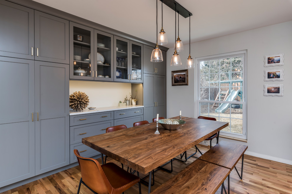 Eat-in kitchen - mid-sized transitional galley medium tone wood floor eat-in kitchen idea in Denver with a farmhouse sink, shaker cabinets, gray cabinets, quartz countertops, white backsplash, porcelain backsplash, stainless steel appliances, a peninsula and white countertops