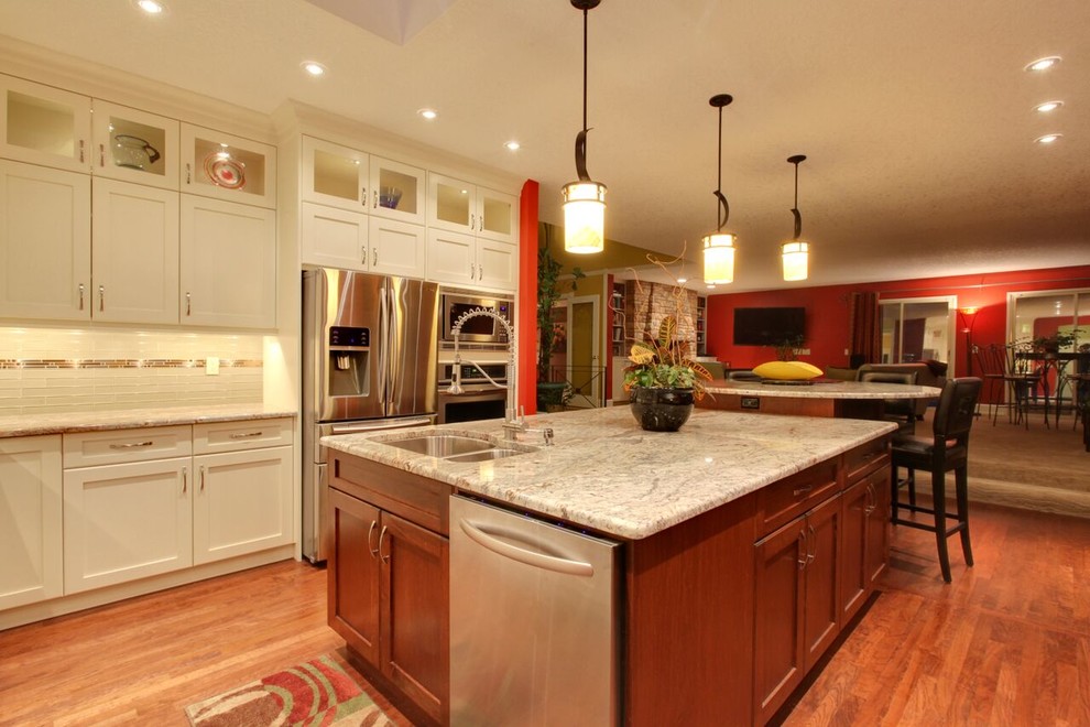 Inspiration for a large transitional u-shaped medium tone wood floor and brown floor eat-in kitchen remodel in Calgary with an undermount sink, shaker cabinets, white cabinets, granite countertops, white backsplash, matchstick tile backsplash, stainless steel appliances and an island