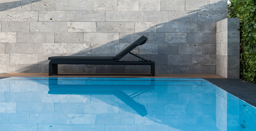 Design ideas for a small modern side yard rectangular lap pool in Stuttgart with natural stone pavers.