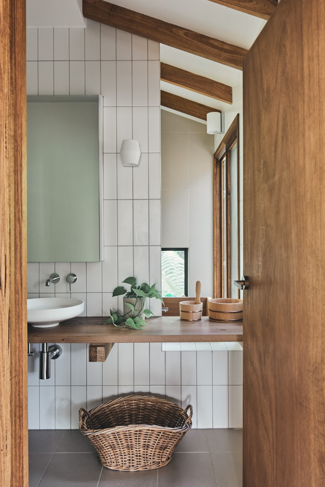 Réalisation d'une salle de bain asiatique en bois brun avec un bain japonais, un carrelage blanc, un plan de toilette en bois et poutres apparentes.