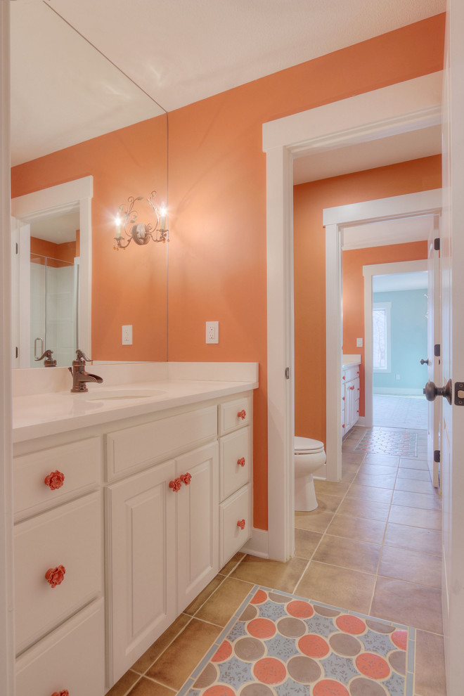 This is an example of a small beach style kids bathroom in Kansas City with raised-panel cabinets, white cabinets, marble benchtops, a one-piece toilet, porcelain tile, red walls, ceramic floors and brown tile.