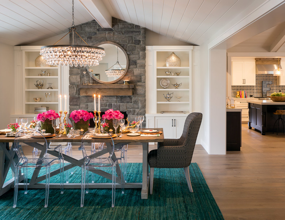 Inspiration for a mid-sized transitional open plan dining in San Francisco with white walls, medium hardwood floors, a standard fireplace, a stone fireplace surround and brown floor.