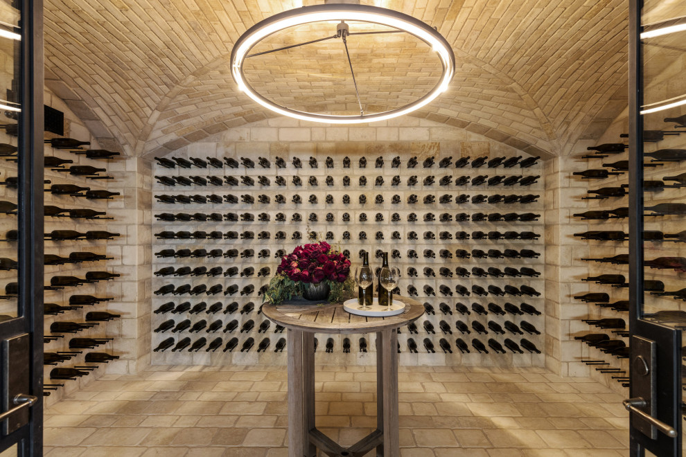 Cette image montre une grande cave à vin minimaliste avec tomettes au sol, un présentoir et un sol beige.