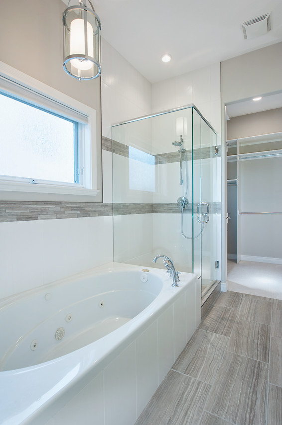 Inspiration for a mid-sized transitional master porcelain tile drop-in bathtub remodel in Calgary with raised-panel cabinets, white cabinets, a two-piece toilet, beige walls, an undermount sink and quartz countertops