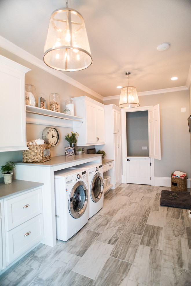 Inspiration for a large country single-wall dedicated laundry room in Atlanta with white cabinets, quartz benchtops, grey walls, porcelain floors, a side-by-side washer and dryer and recessed-panel cabinets.