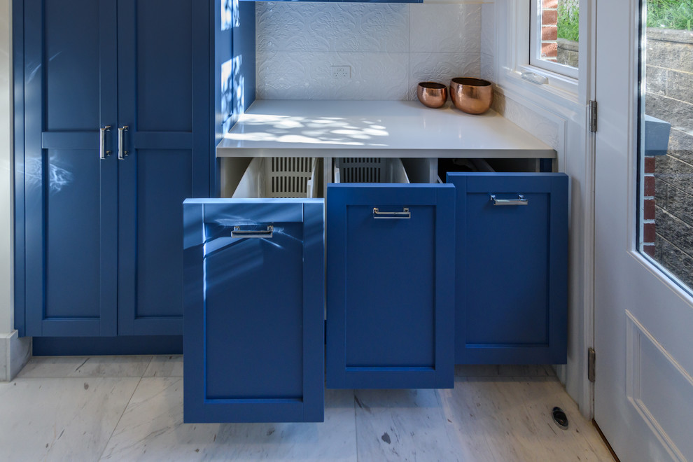 Inspiration for a large traditional galley dedicated laundry room in Melbourne with a drop-in sink, shaker cabinets, blue cabinets, quartz benchtops, white walls, marble floors and a side-by-side washer and dryer.