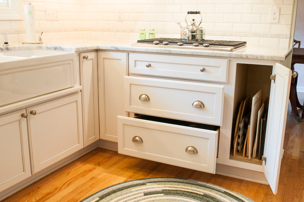 Small transitional u-shaped medium tone wood floor enclosed kitchen photo in Milwaukee with a farmhouse sink, shaker cabinets, white cabinets, granite countertops, white backsplash, subway tile backsplash, stainless steel appliances and a peninsula