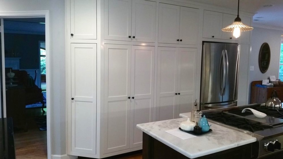 Mid-sized transitional galley medium tone wood floor open concept kitchen photo in Richmond with an undermount sink, recessed-panel cabinets, white cabinets, quartzite countertops, black backsplash, stone slab backsplash, stainless steel appliances and an island