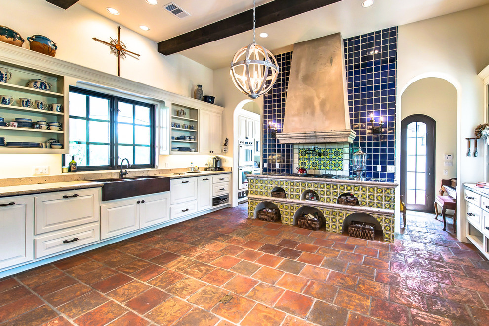 Photo of a mid-sized country galley eat-in kitchen in Austin with a farmhouse sink, limestone benchtops, blue splashback, terra-cotta splashback, terra-cotta floors and no island.