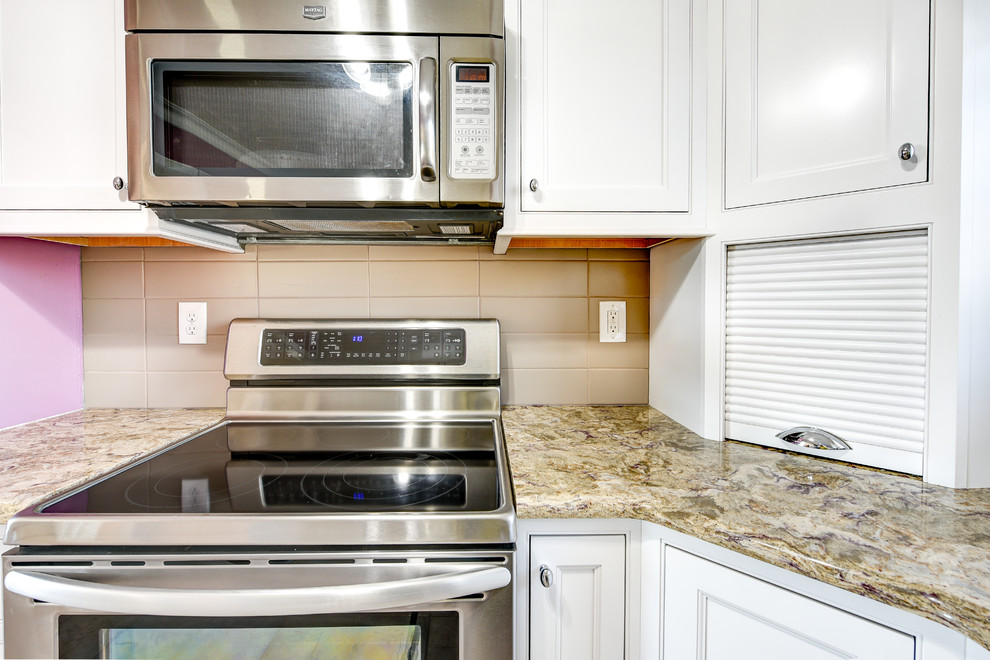 Example of a mid-sized classic u-shaped ceramic tile eat-in kitchen design with an undermount sink, recessed-panel cabinets, white cabinets, granite countertops, beige backsplash, ceramic backsplash, stainless steel appliances and no island
