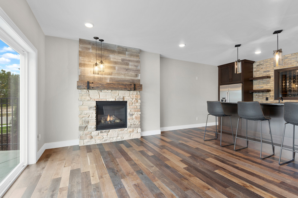 Basement - large transitional walk-out medium tone wood floor, brown floor and brick wall basement idea with a bar, a standard fireplace and a stone fireplace