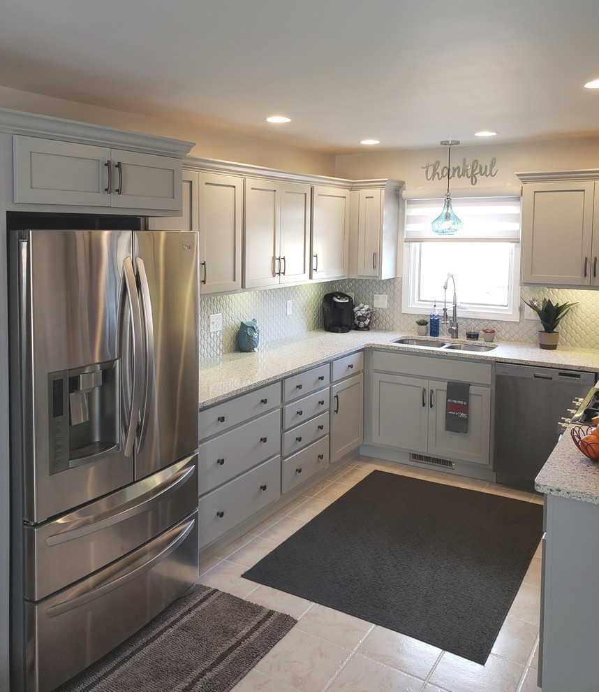 Example of a mid-sized transitional u-shaped ceramic tile and white floor enclosed kitchen design with an undermount sink, shaker cabinets, gray cabinets, quartz countertops, gray backsplash, cement tile backsplash, stainless steel appliances, no island and gray countertops