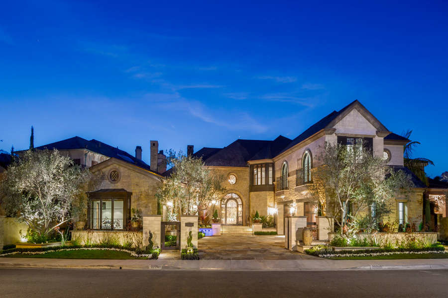 Photo of a large mediterranean two-storey brown house exterior in Orange County with stone veneer and a gable roof.