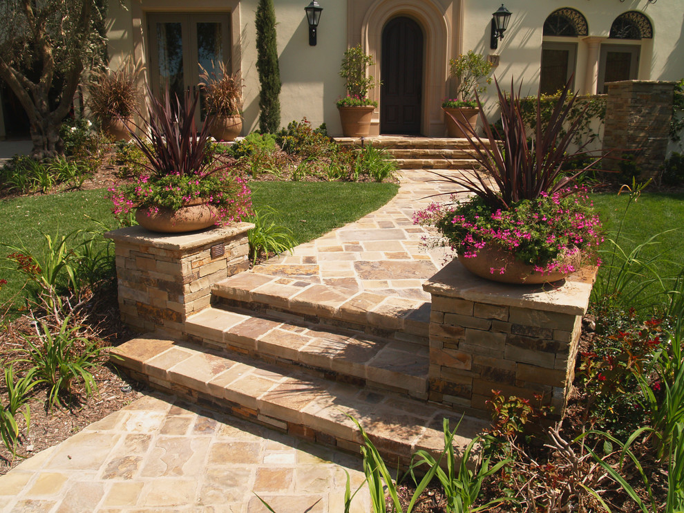 Design ideas for a mid-sized mediterranean front yard full sun formal garden for summer in Orange County with natural stone pavers and a garden path.