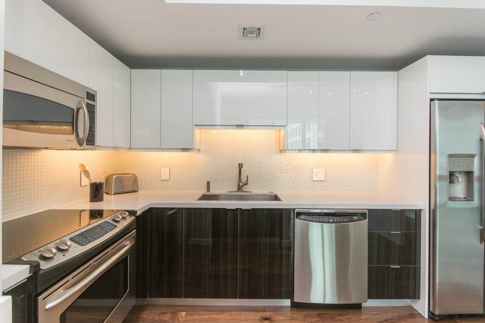 Small modern u-shaped kitchen in Miami with an undermount sink, flat-panel cabinets, white cabinets, quartzite benchtops, white splashback, glass tile splashback, stainless steel appliances and with island.