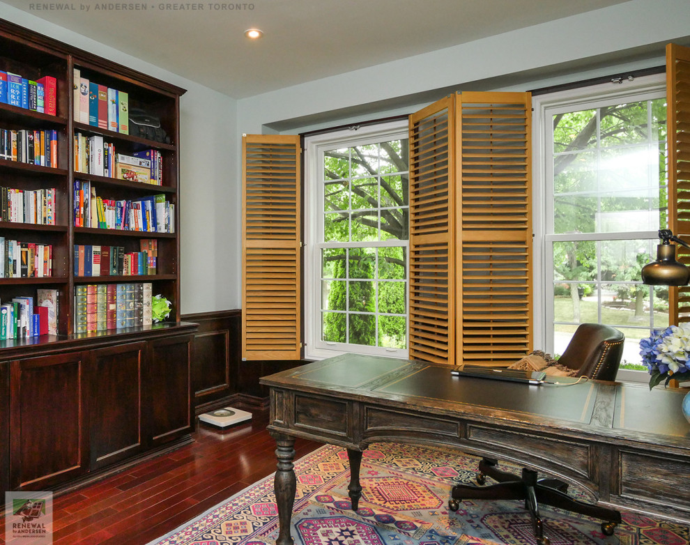 This is an example of a home office in Toronto with green walls, dark hardwood floors, no fireplace, a freestanding desk, multi-coloured floor and decorative wall panelling.