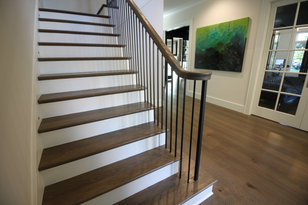 Large transitional wood l-shaped staircase in DC Metro with painted wood risers, metal railing and panelled walls.