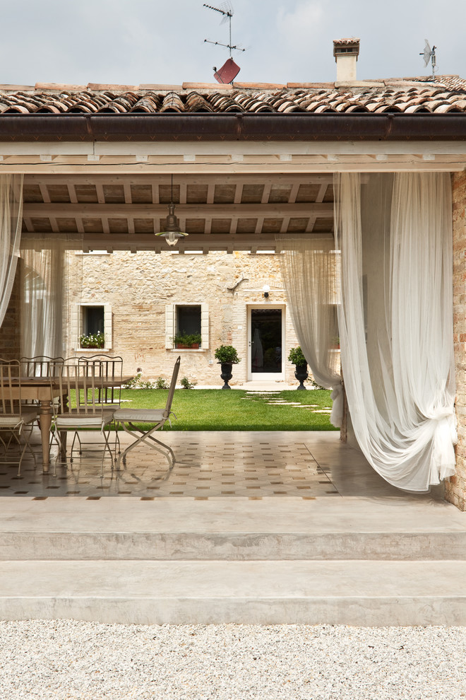 This is an example of a country backyard patio in Other with concrete pavers.