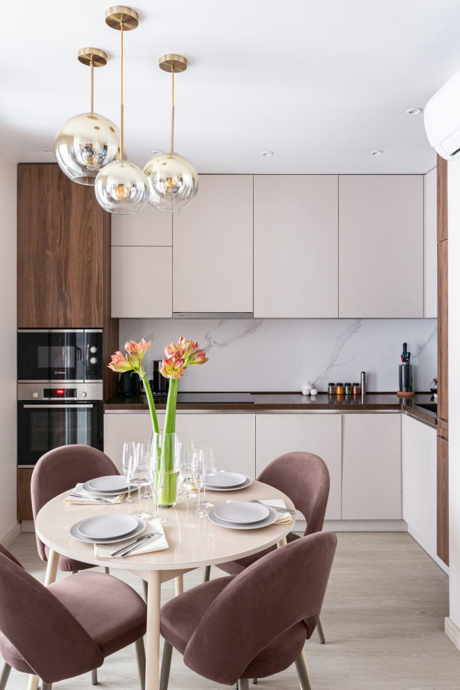 Mid-sized contemporary l-shaped eat-in kitchen in Moscow with an undermount sink, flat-panel cabinets, beige cabinets, white splashback, porcelain splashback, panelled appliances, beige floor and brown benchtop.
